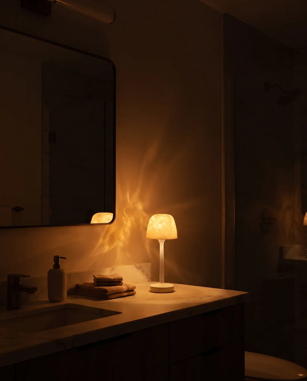 The same bathroom at night lit only by warm amber lamplight
