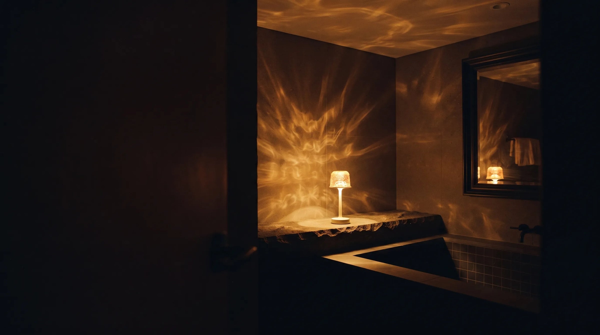 A dark bathroom at night lit only by the warm amber glow of a Hush Ember® lamp